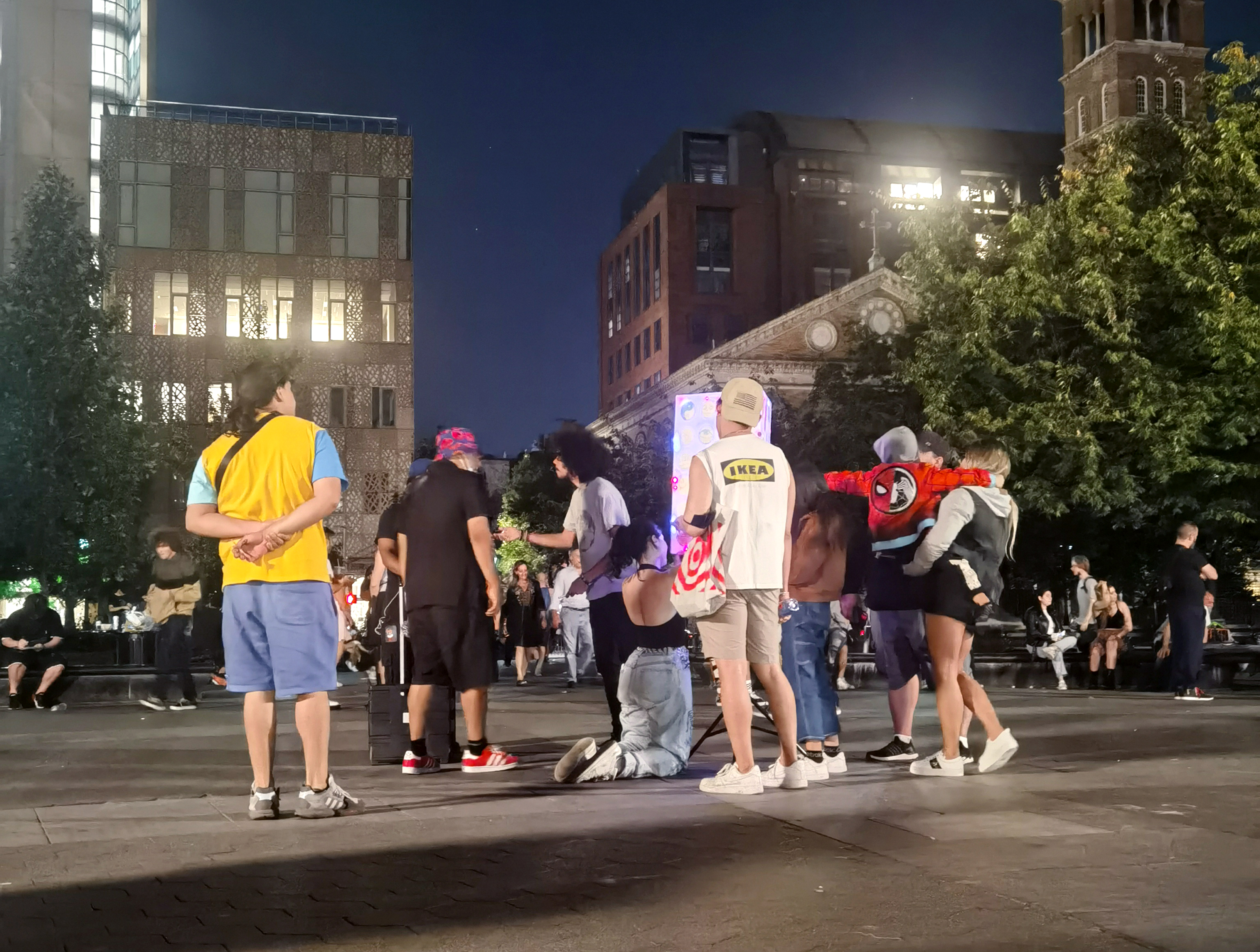 At night, a crowd of people looking at and drawing on the collective art installation